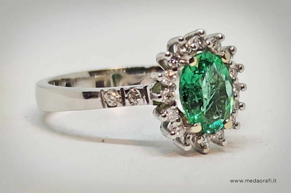 Vista di tre quarti di anello in oro bianco con smeraldo taglio ovale e diamanti con griffes a triangolo