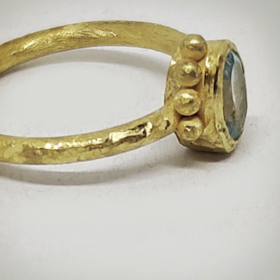 Dettaglio del fianco di un anello in oro grezzo e acquamarina