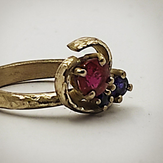 Dettaglio del catone di un anello di fidanzamento artigianale in oro con rubino e zaffiri